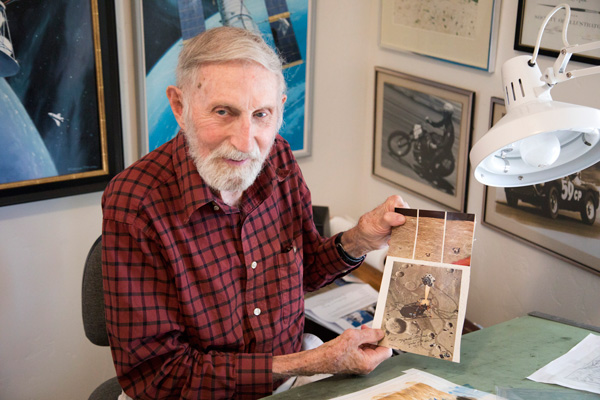 Pierre Mion holds a page from National Geographic with his painting of Eagle lifting off from the Moon